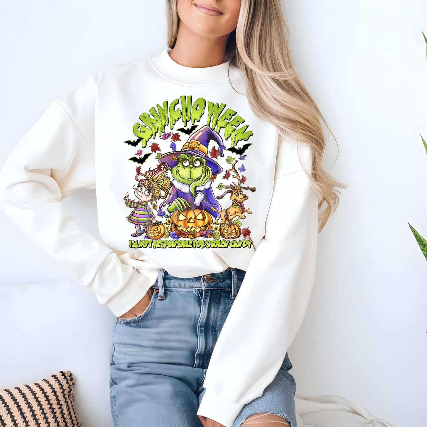 Woman wearing Grinch 2 Halloween Sweatshirt featuring spooky Grinch design in cozy white fleece, perfect for fall fashion.