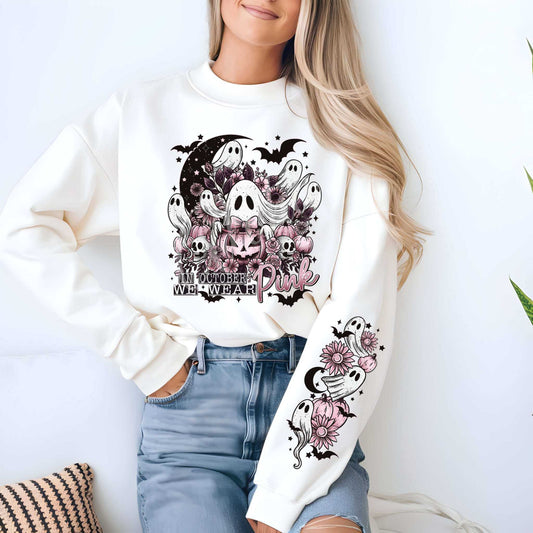 Woman wearing "In October We Wear Pink" breast cancer awareness sweatshirt with ghost graphics, smiling, casual outfit, cozy pink support